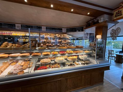 Une boulangerie accueillante avec un choix de pains et de gâteaux frais. Au premier plan, une tasse de café et une assiette avec une pâtisserie.