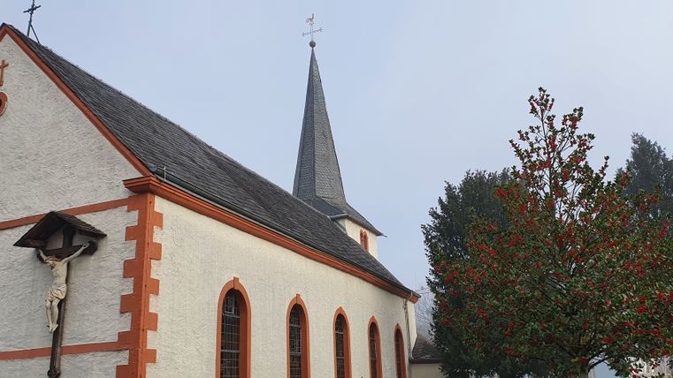 Church with red border and cross on the façade, next to it a tree with red berries.