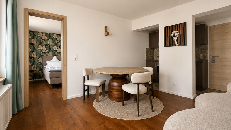Een modern ingericht woonruimte met een ronde tafel en lichte stoelen. Op de achtergrond ziet men een toegang tot een slaapkamer met stijlvolle behang.