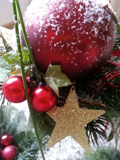 Une décoration de Noël avec une boule rouge, des étoiles dorées et des baies rouges. La neige recouvre la couche supérieure, ce qui crée une ambiance festive.