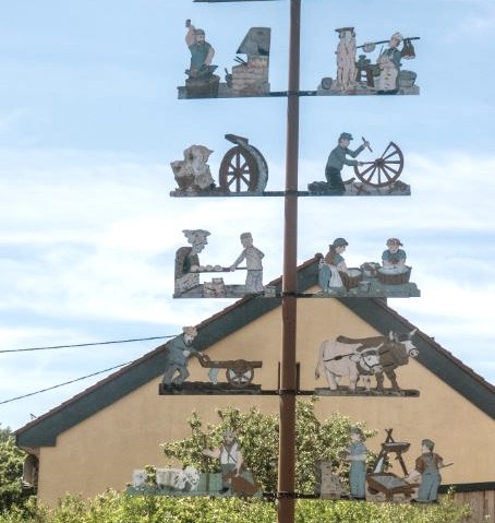 A maypole with handcrafted figures stands in front of a house in Trimport. Street sign: Teitelbacher Straße., © TI Bitburger Land