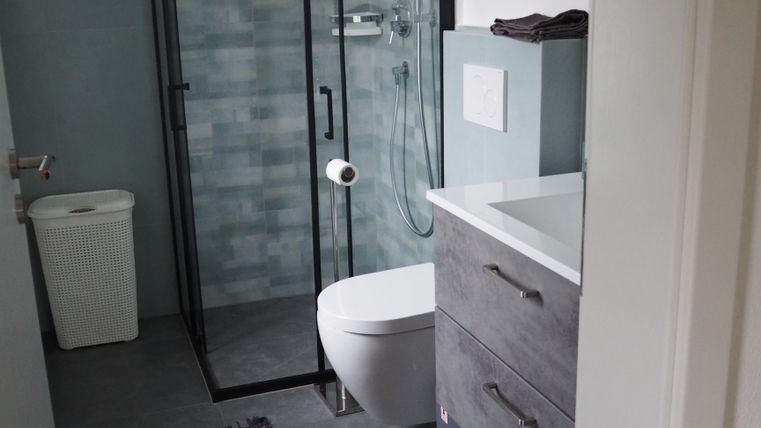 Ein modernes Badezimmer mit einer Dusche, einem WC und einem Waschbecken. Der Raum ist in sanften Farben gehalten und wirkt geräumig und sauber.