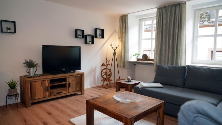 A modern living space with a gray sofa, a wooden table, and a television. The television has an HDMI port for your entertainment system (e.g., FireTV Stick, PlayStation, etc.).