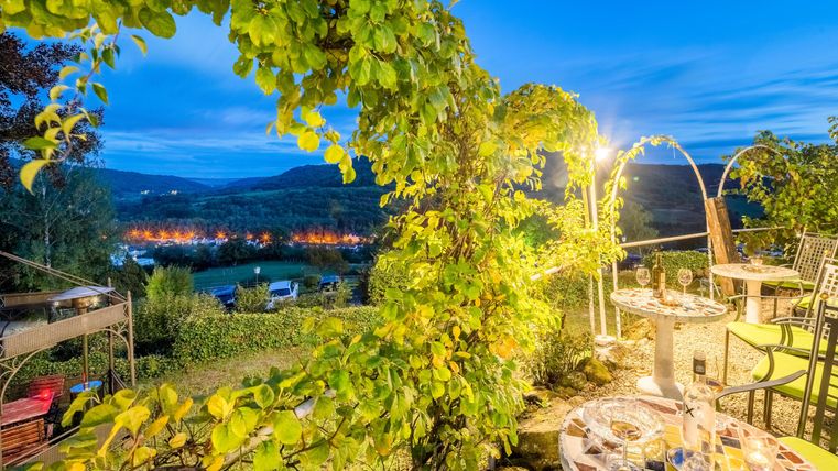 Een mooi uitzicht op het Rosenterras met wijnstokken en een sfeervol avondlicht. Tafels zijn voorbereid voor gasten in de open lucht.