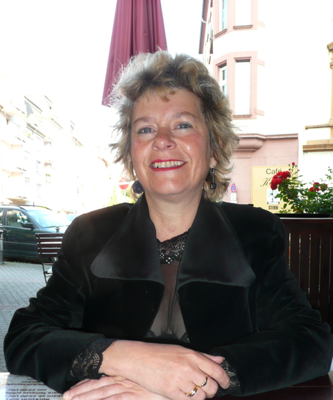 Eine Gruppe von fünf Musikern steht auf einer Bühne. Sie halten verschiedene Musikinstrumente und tragen elegante schwarze Kleidung.