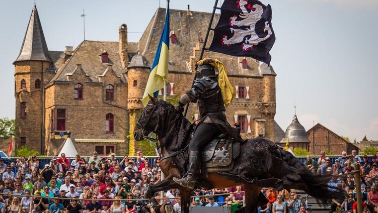 Ridder op paard met vlag en op de achtergrond kasteel Satzvey