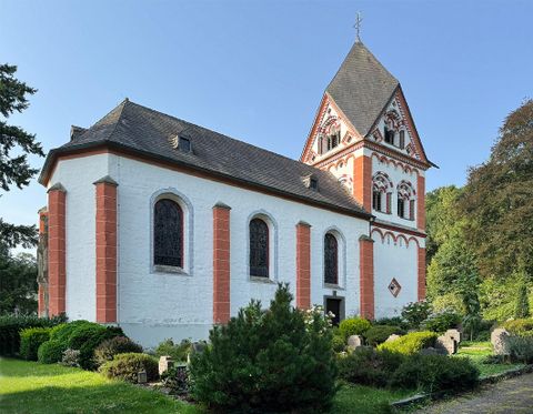 Eine beeindruckende Kirche mit markanten Türmen und einem schönen Eingang. Die Umgebung besteht aus einem gepflegten Platz und Bäumen im Hintergrund.