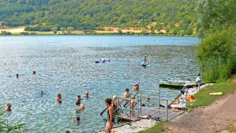 Ein schöner See mit vielen Menschen, die schwimmen und paddeln. Die Umgebung ist grün und einladend.