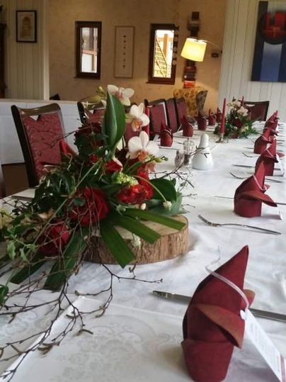 A festively set table with red napkins and a floral arrangement. The atmosphere feels cozy and inviting.