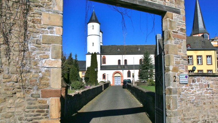 Un bâtiment historique doté d'une tourelle blanche caractéristique et d'un beau mur. Le ciel bleu limpide confère à la scène une atmosphère chaleureuse.