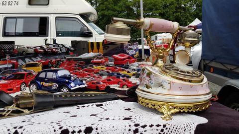 An antique market with an old telephone and various toy cars in the background. The table is decorated with a crocheted blanket.