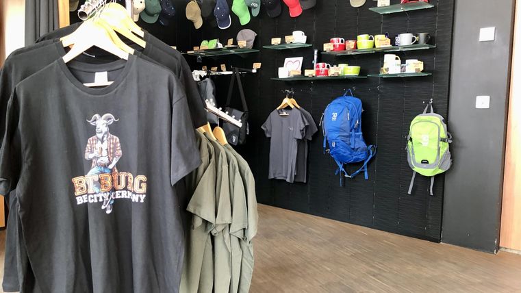 Une zone de vente avec des t-shirts, des bonnets et des sacs à dos. L'atmosphère est moderne et accueillante.