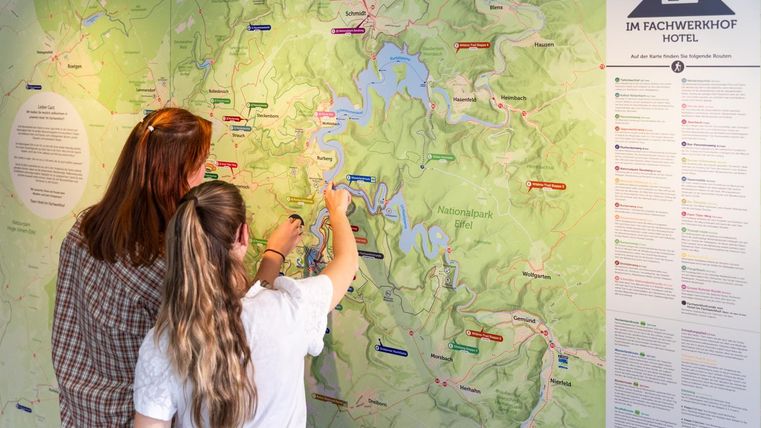 Twee personen bekijken een kaart en markeren plekken. Op de achtergrond zijn informatie over de omgeving te zien.