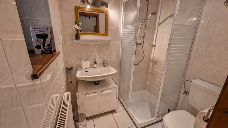 Ein modernes Badezimmer mit Dusche, Waschbecken und Toilette. Die Wände sind hell gefliest und es gibt einen kleinen Spiegel.