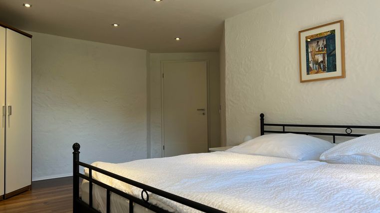 Ein gemütliches Schlafzimmer mit einem Doppelbett und einem Kleiderschrank. Die Wände sind weiß und es gibt ein kleines Bild an der Wand.