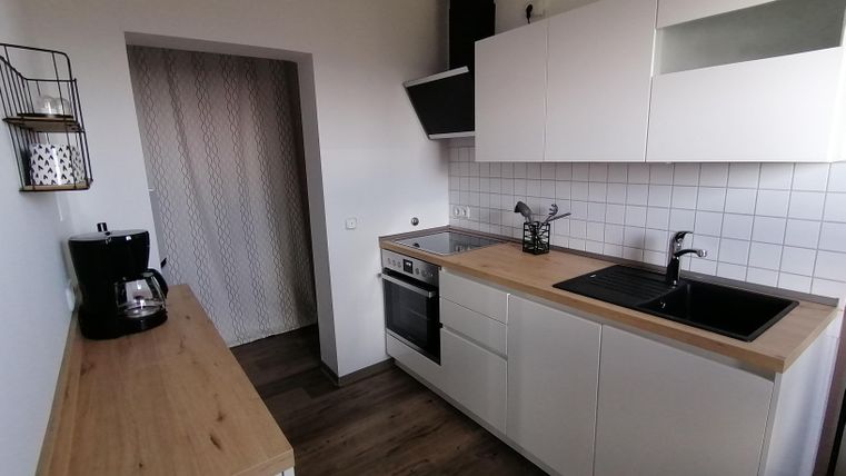 Eine moderne Küche mit weißen Schränken und einer Holzarbeitsplatte. Der Raum ist hell und freundlich gestaltet.