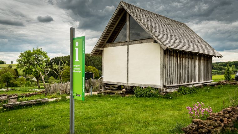 Een informatiebord voor een historisch gebouw in een groen landschap.