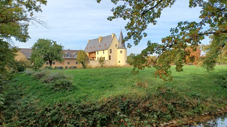 Langendorf Castle with green lawn and trees in the foreground.