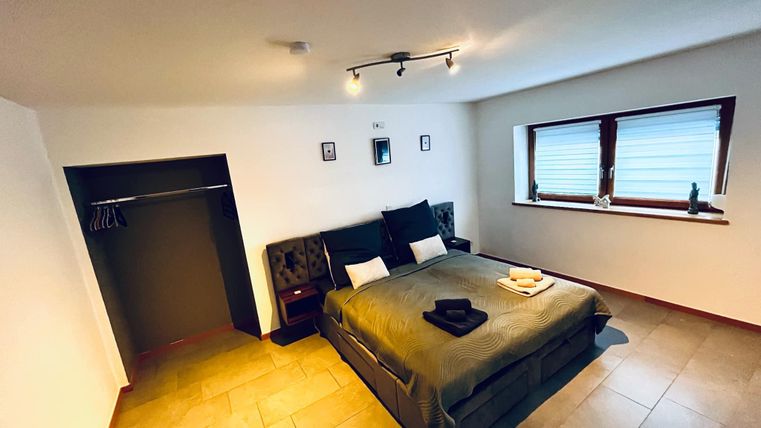 Een modern ingerichte slaapkamer met een groot stapelbed en een eenvoudig ontwerp. Er is een raam met jaloezieën en een kledingkast.