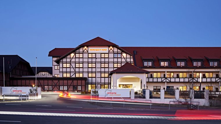Ein modernes Hotelgebäude mit traditioneller Architektur. Die Fassade ist bunt beleuchtet im Abendlicht.