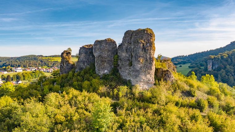 Formation rocheuse des Dolomites de Gerolstein dans l'Eifel, entourée d'un paysage vert et d'un ciel bleu.