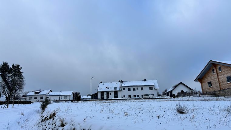 A snowy landscape with several houses. The sky is cloudy and a calm winter atmosphere can be seen.
