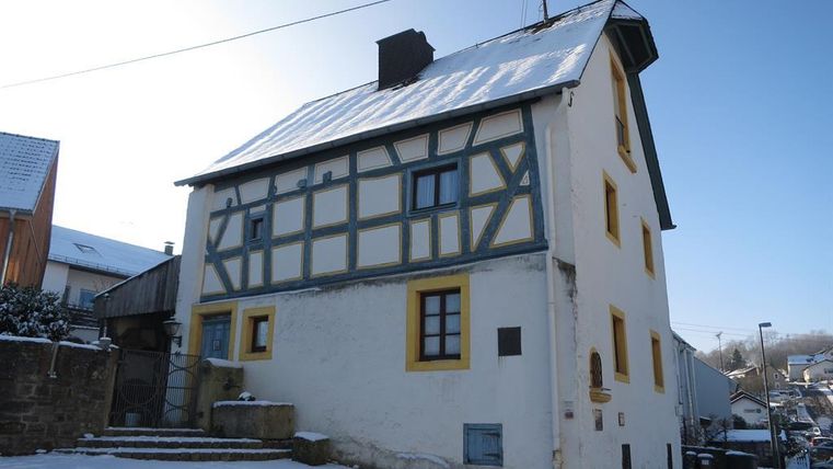 A charming half-timbered house lying in the snow. The sky is clear and radiant blue.