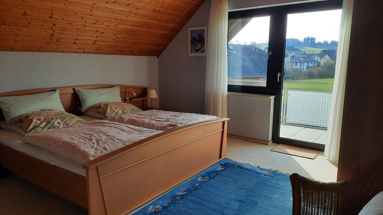 Une chambre confortable avec un lit double et des couleurs douces. De grandes fenêtres offrent une vue sur les environs.