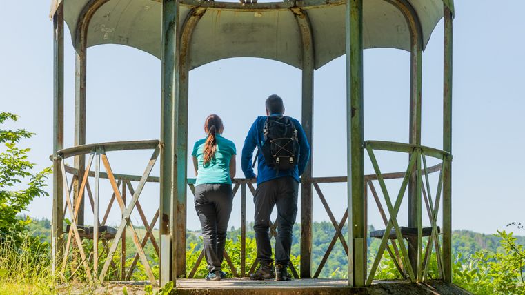 Zwei Personen stehen in einem Pavillon und blicken in die Landschaft.