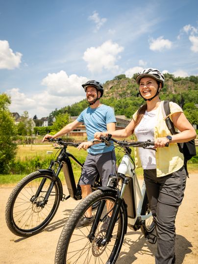 Two people with bicycles in the Gerolstein spa gardens in sunny weather.