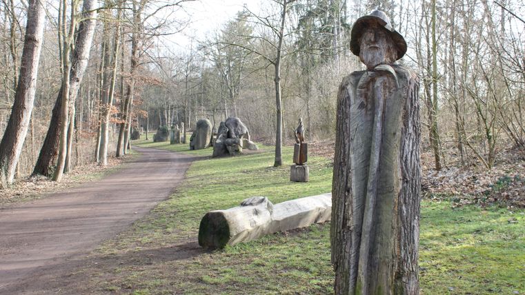 Einige Skulpturen am Wegesrand. Vorne eine Skulptur eines Menschen 