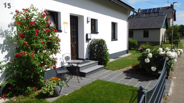 Ein schönes Haus mit einem gepflegten Vorgarten. Blumen und eine gemütliche Sitzecke laden zum Entspannen ein.