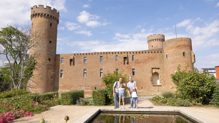 Family in front of the Landesburg Zülpich with pond in the foreground.