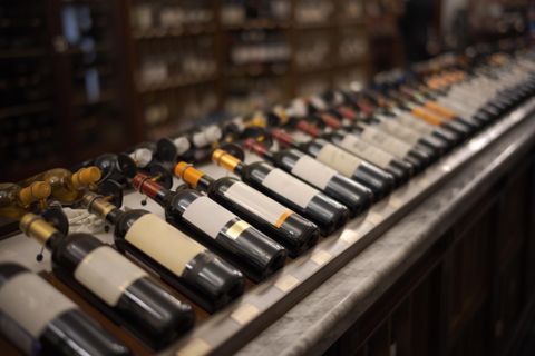 Eine Reihe von Weinen in Flaschen an einer Theke. Die Flaschen haben unterschiedliche Etiketten und Farben.