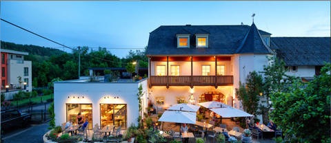 Restaurant de vin accueillant avec des vignes vertes en arrière-plan. Des offres pour des réservations de table et des événements spéciaux sont présentées.