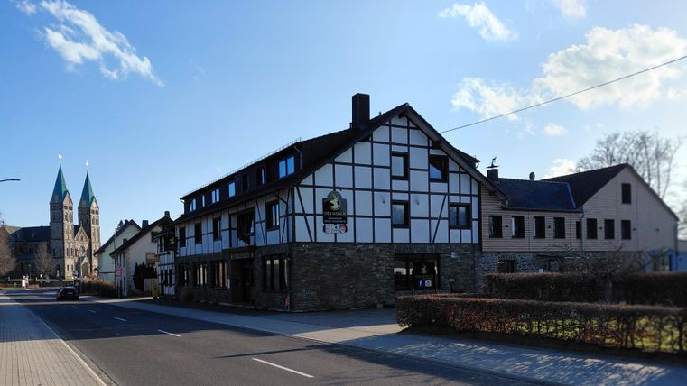 Une charmante maison à colombages avec un café de rue. En arrière-plan, deux flèches d'église sont visibles.