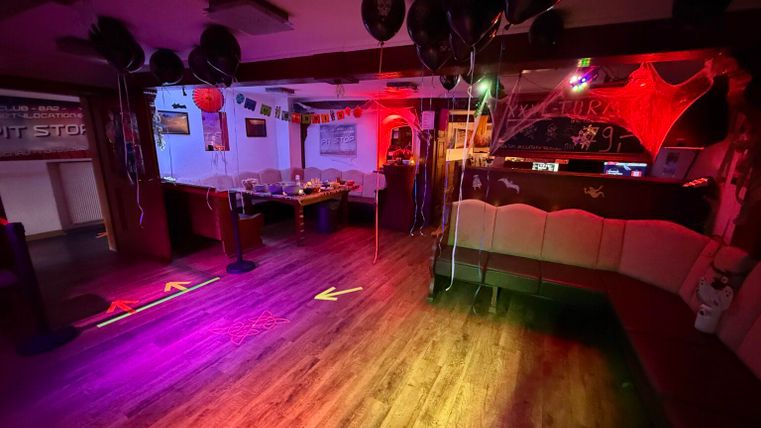 Een sfeervolle ruimte met kleurrijke lichten en ballonnen. De inrichting is feestelijk en uitnodigend.