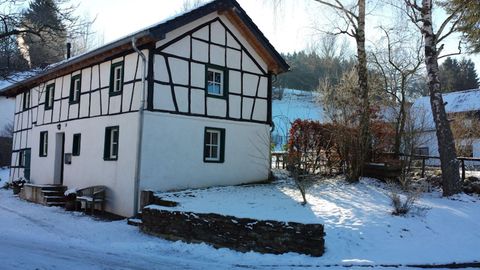 A traditional half-timbered house in a snow-covered landscape. The sky is clear and the surroundings are quiet.