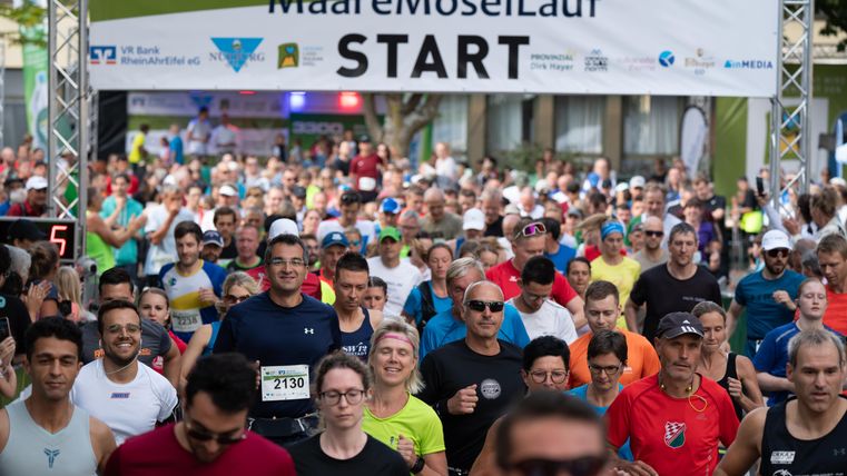 Eine große Gruppe von Läufern beginnt den MaareMoselLauf. Im Hintergrund ist ein Banner mit dem Schriftzug „START“ sichtbar.