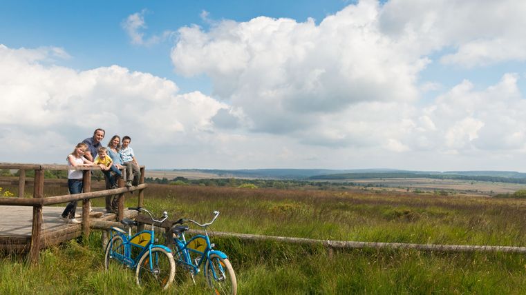 Famille sur une plateforme en bois dans les Hautes Fagnes avec des vélos au premier plan.
