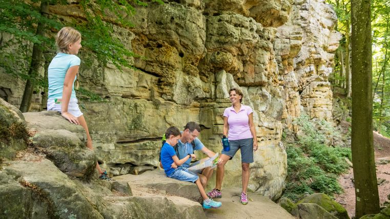 Gezin neemt pauze voor een rotswand in het bos.