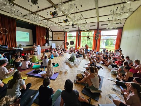 Eine malerische Aussicht auf eine Burgruine, umgeben von grünen Wäldern. Im Hintergrund sind sanfte Hügel und ein klarer Himmel zu sehen.