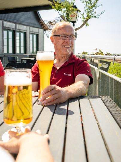 Mann genießt sein Bier im Biergarten mit Blick auf die Hocheifel