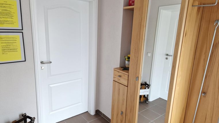 Entree met een witte deur en een garderobekast