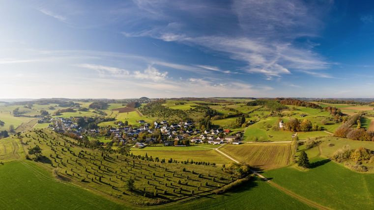 Landscape view of Alendorf and Calvary in the Eifel with green fields and blue sky.