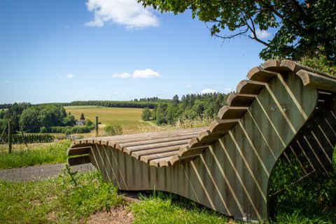 Houten bank met uitzicht op een groen landschap en blauwe lucht in Neidenbach.
