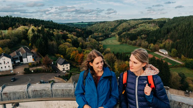 Deux femmes se tiennent sur une plate-forme d'observation avec vue sur un paysage boisé.