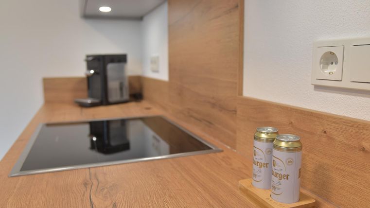 Eine moderne Küche mit Holzarbeitsplatte und integrierter Kochzone. Auf dem Tisch stehen zwei Dosen in einem Holzständer.