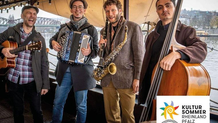 Four musicians are on a boat playing different instruments. In the background, there is a beautiful view of the city.