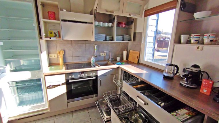 Une cuisine moderne avec des étagères ouvertes et un réfrigérateur. Elle comprend un four, un évier et divers appareils de cuisine.